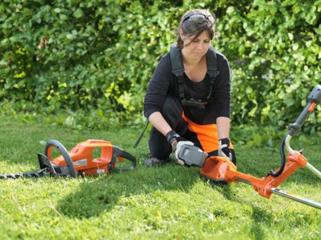 Woman changing battery for mower - Toowoomba Outdoor Power Products in Glenvale, QLD